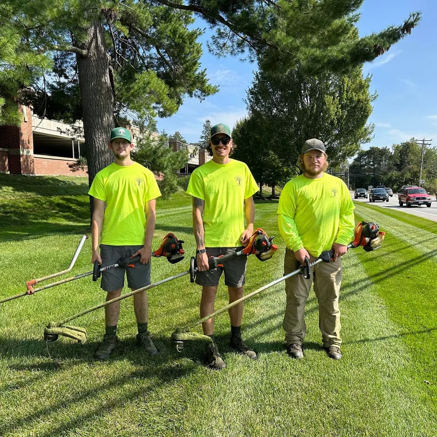 Kyle Poirier Landscaping LLC crew with trimmers on freshly mowed commercial property